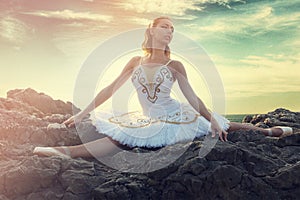 Young ballerina making a splits on rocks