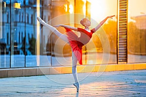 Young ballerina in a red tutu is dancing against backdrop of cityscape