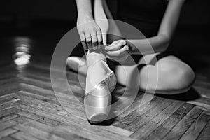 Young ballerina sitting, legs and golden shoes. Classical art concept. Preparing for dance. closeup. Black and white