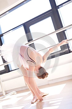 Young Ballerina Stretching at Barre in Studio