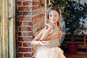 Young ballerina in tutu and pointe ballet shoes practicing dance moves in the dancing hall.