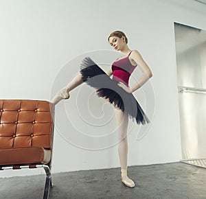 young ballerina in a tutu and pointe shoes is sitting on an armchair