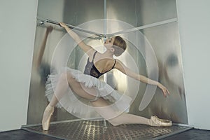 young ballerina in a tutu and pointe shoes standing at the ballet barre poses ballet elements