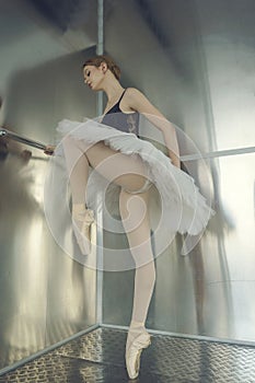 young ballerina in a tutu and pointe shoes standing at the ballet barre poses ballet elements