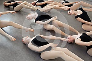 Young ballerinas do complex exercises in ballet school.