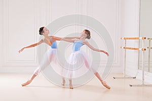 Young ballerinas having rehearsal at studio. Row of happy young ballerinas practicing at ballet barre, focus on first girl
