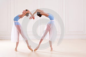 Young ballerinas having rehearsal at studio. Row of happy young ballerinas practicing at ballet barre, focus on first girl