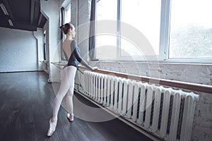 Young ballet dancer practice movement looking out the window in studio active lifestyle