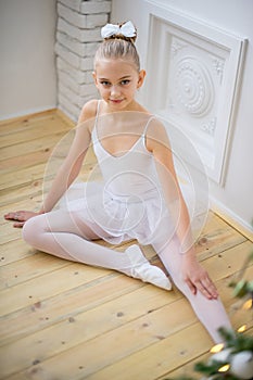 Young ballet dancer sitting near Christmas tree