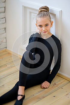 Young ballet dancer sitting near the wall