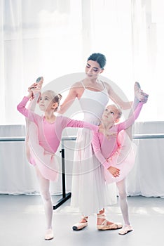 young ballet teacher exercising with small ballerinas