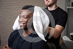 Young barber dries clients hair with soft towel