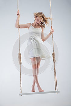 Young bare-footed girl on swing looking down.