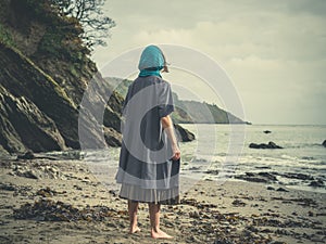 Young barefoot woman with headscarf on beach