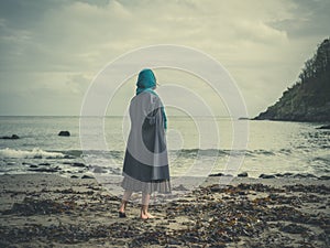 Young barefoot woman with headscarf on beach