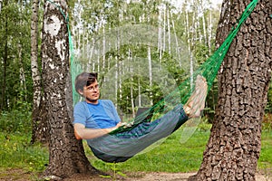 Young barefooted man in glasses with reclines in hammock