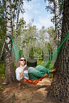 Young barefooted woman in dark sunglasses lies in hammock photo