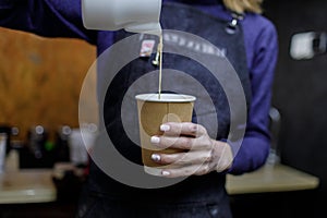 Young barista girl pouring a cappuccino glass