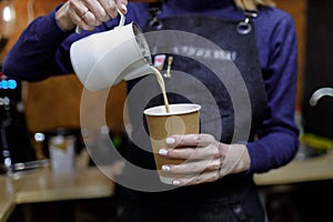 Young barista girl pouring a cappuccino glass