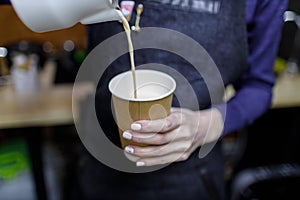 Young barista girl pouring a cappuccino glass