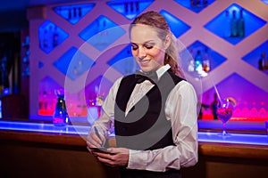 Young barmaid writing in notepad