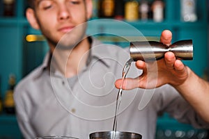 Young Barman's making shot cocktail, pouring alcohol into glass