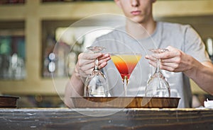 Young bartender or a waiter making a cocktail