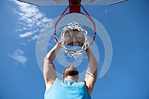 Young basketball player dunking basketball on outdoor court.