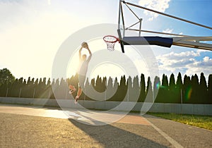 A young basketball player flying towards the rim for a slam dunk.