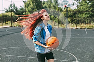 A young basketball player is training on an outdoor basketball court, a teenage girl is playing basketball. Basketball