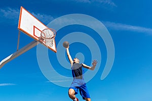 Young Basketball street player making slam dunk