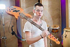 Young bass player with tattoo standing with guitar