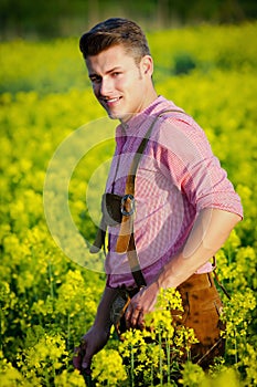 Young bavarian man standing in a field of yellow flowers
