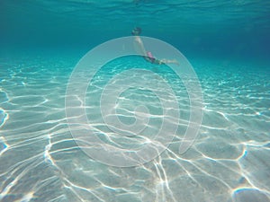 Young beard man with glasses diving in a blue clean water