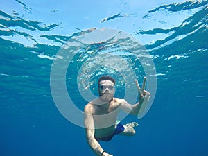 Young beard man with mask diving in a clean water