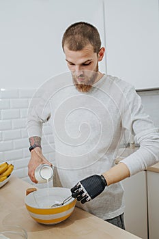 Young bearded attractive guy with artificial limb  cooks in the kitchen
