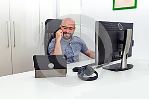 Young bearded bald man with eyeglasses working remote from home during the pandemic lock down. Caucasian male at the office desk