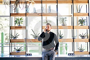 Young bearded business man in office talking at mobile phone in modern office