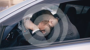 Young bearded business man sitting in car very upset and stressed after hard failure and moving in traffic jam