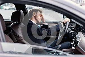 Sad businessman driving alone in his new car