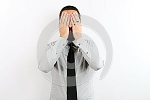 Young bearded businessman with shirt and tie on isolated white background covers his face with his hands