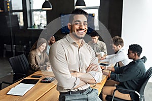 Young bearded businessman sitting on desk and posing photo