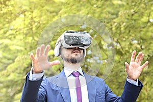 Young bearded businessman in suit uses virtual reality glasses a