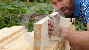 Young bearded carpenter checks the quality of the boards. slow motion