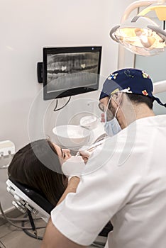 Young bearded male dentist drilling tooth to female patient