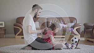 Young bearded father brushing the hair of his little girl while the child combing the tail of her toy horse sitting on