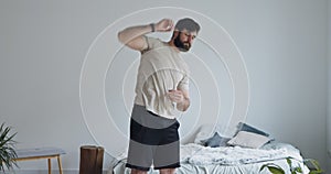 Young bearded guy training at home, doing stretching exercise