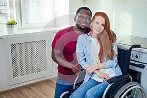 Young bearded handicapped redhaired ginger wife in wheelchair and her african american husband at kichen