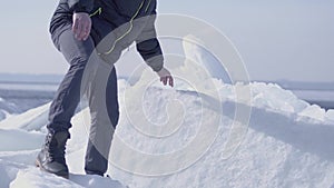 Young bearded handsome man in warm jacket,hat and boots climbling the glacier. Amazing nature of a snowy glacier. The