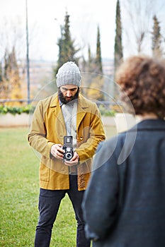 Young bearded hipster taking photo to redhead girl with TLR came